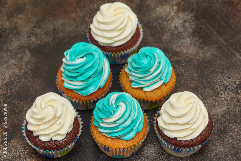 Cupcakes with turquoise and white buttercream frosting on brown background Cupcakes with turquoise and white buttercream frosting on brown background