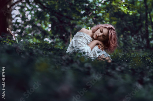 Beauty woman in fairy nature scenery. Sitting in the grass bowed head to toe