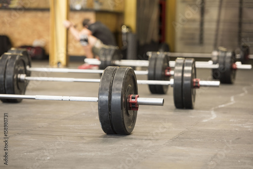 Close-up of Weightlifting Barbells in a neat row loaded with heavy weights ready for a class or competition to begin with gym background 