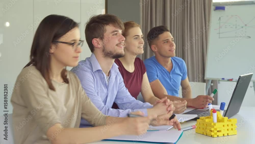 Young caucasian managers watching something together at the office. Pretty brunette girl in glasses preparing to note. Handsome bearded guy opening his mouth in surprise Young caucasian managers watching something together at the office. Pretty brunette girl in glasses preparing to note. Handsome bearded guy opening his mouth in surprise