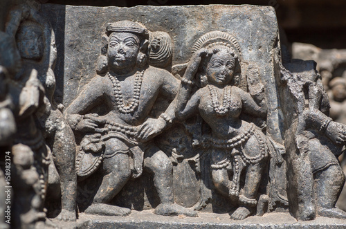 Woman and man in traditional style dancing on relief of the 12th century Hoysaleshwara temple in Halebidu, India.