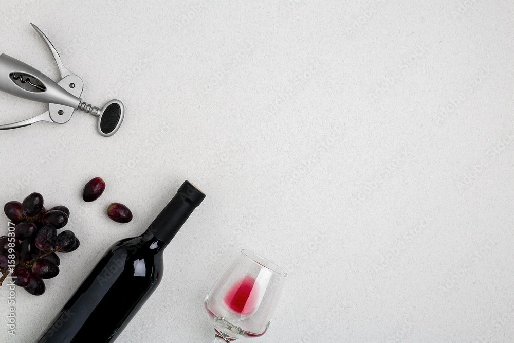 Overhead angled view of a large bottle of red wine, drinking glass on white background