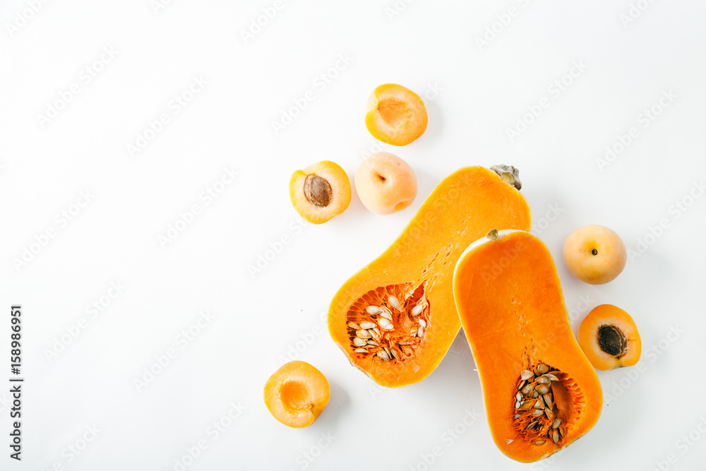 Butternut squash halved with apricots on white background with copy space. Organic food concept.