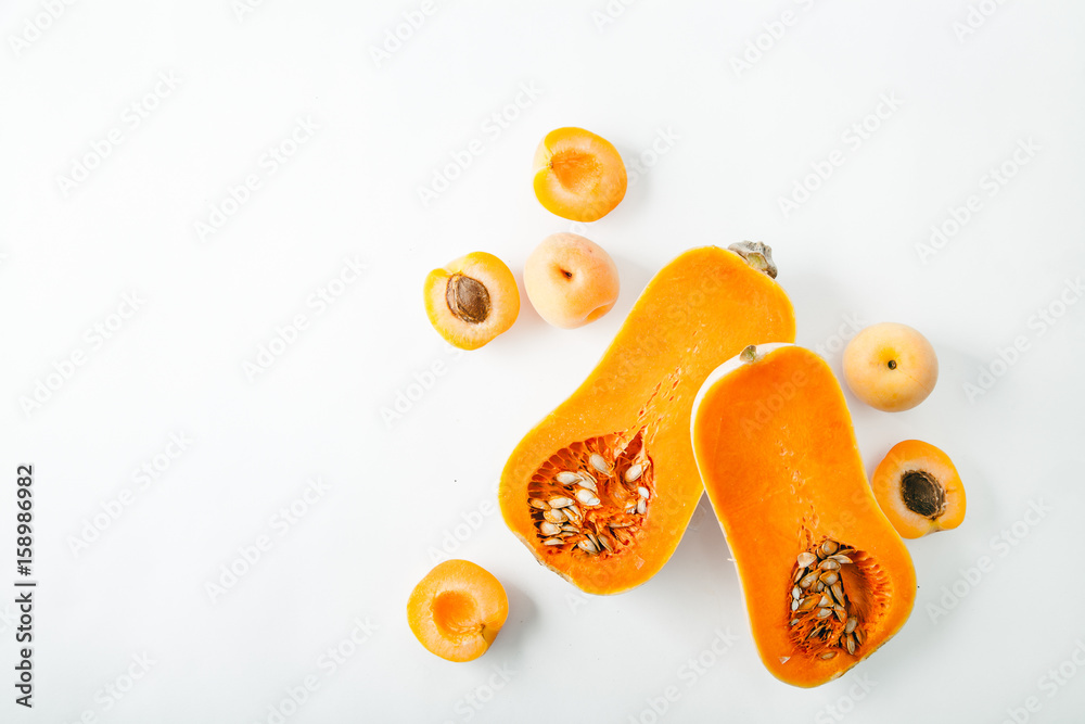 Butternut squash halved with apricots on white background with copy space. Organic food concept.
