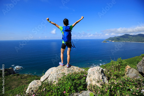 successful woman backpacker open arms on seaside mountain peak © lzf
