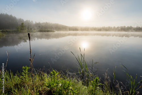 reflections in the lake water in the morning mist