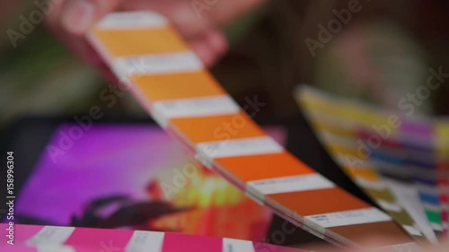 Selection of colors for the Panton system. Shades of pink on Panton's fan: the artist compares the color of the picture and the pantone. Color Palette Guide. Creative people workplace.