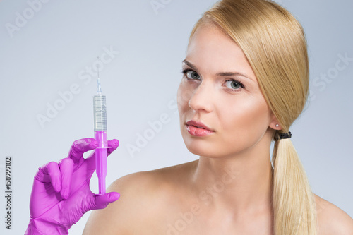 Pretty woman holding syringe in hand in glove