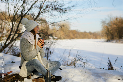 Woman in the morning outdoors drinking tea resting  snow  river  space  card