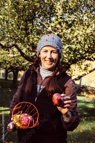 Portrait of woman holding fruit picker and fresh apple photo