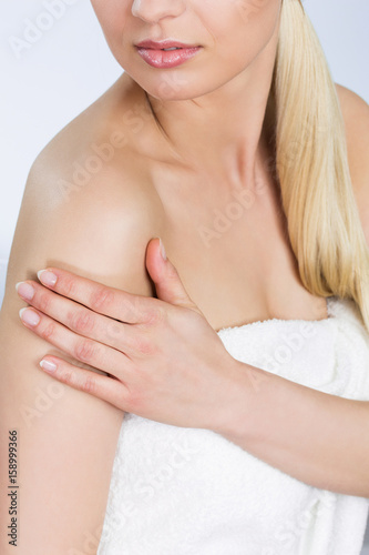 Young woman in towel with hand on arm
