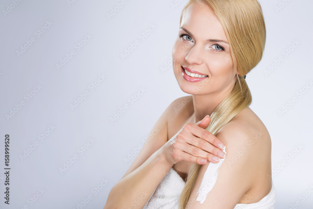 Beautiful blond woman applying cream on arm Beautiful blond woman applying cream on arm