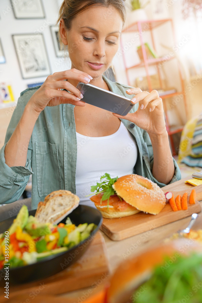 Trendy girl in restaurant taking picture of colourful dish with smartphone Trendy girl in restaurant taking picture of colourful dish with smartphone