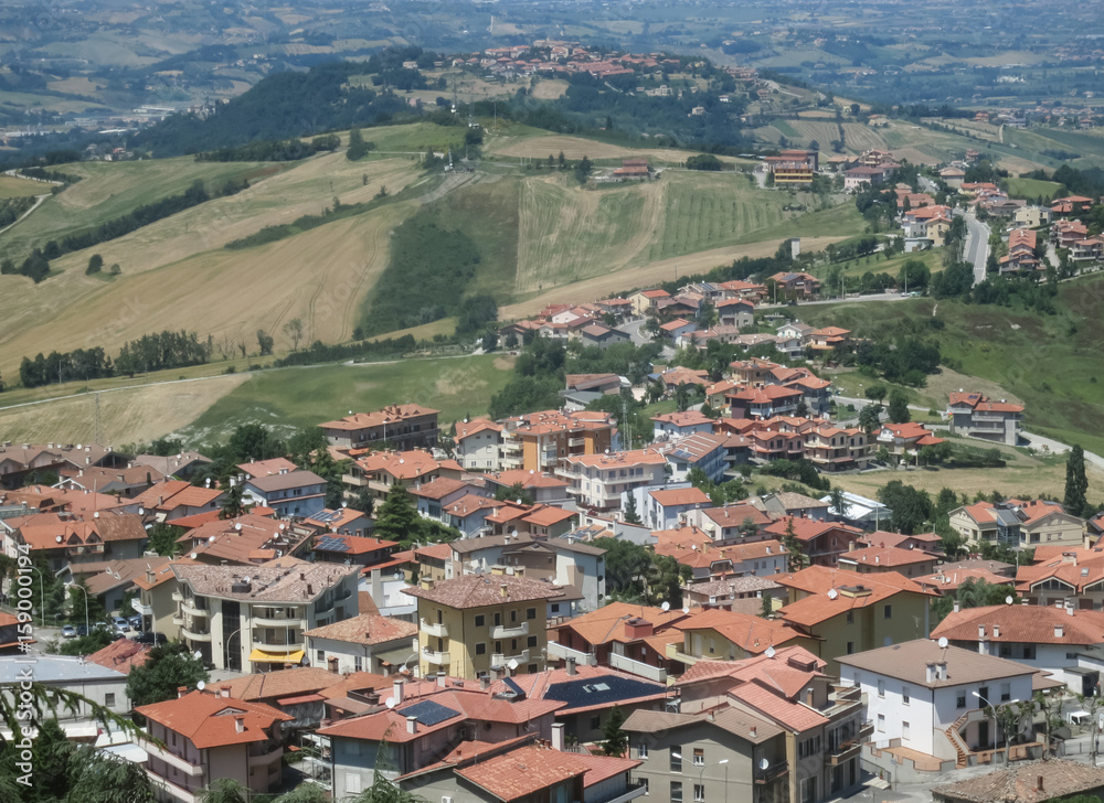 оранжевые черепичные крыши домов итальянского городка на фоне живописных холмов