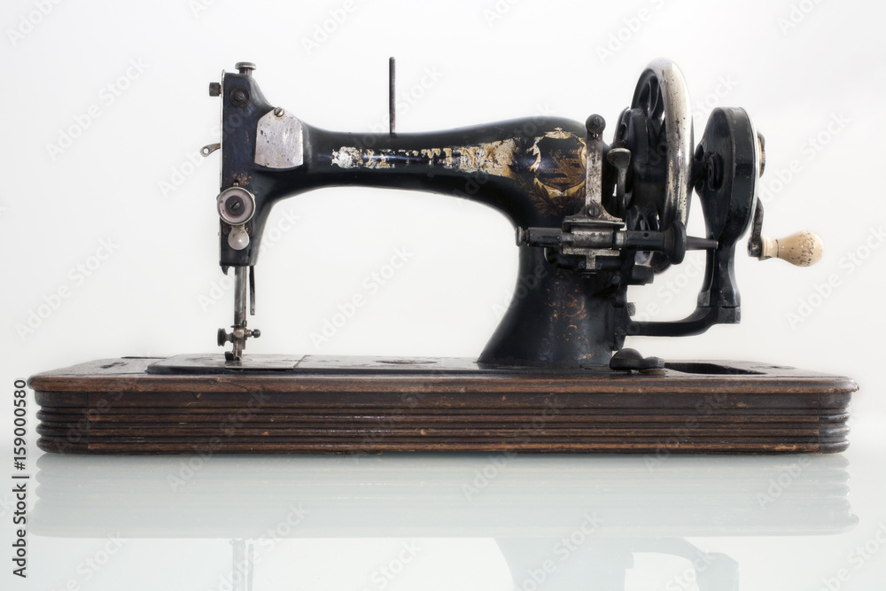 старинная швейная машинка с ручным приводом на белом фоне