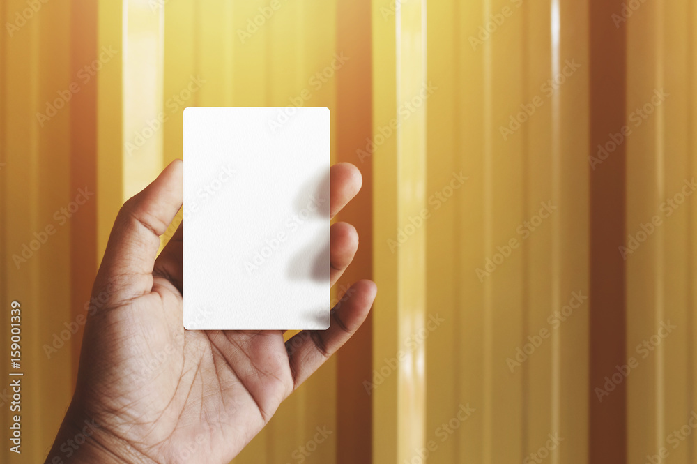 Obraz premium Hand holding Blank business card for mock up, present over yellow gold background, Warm tone filter