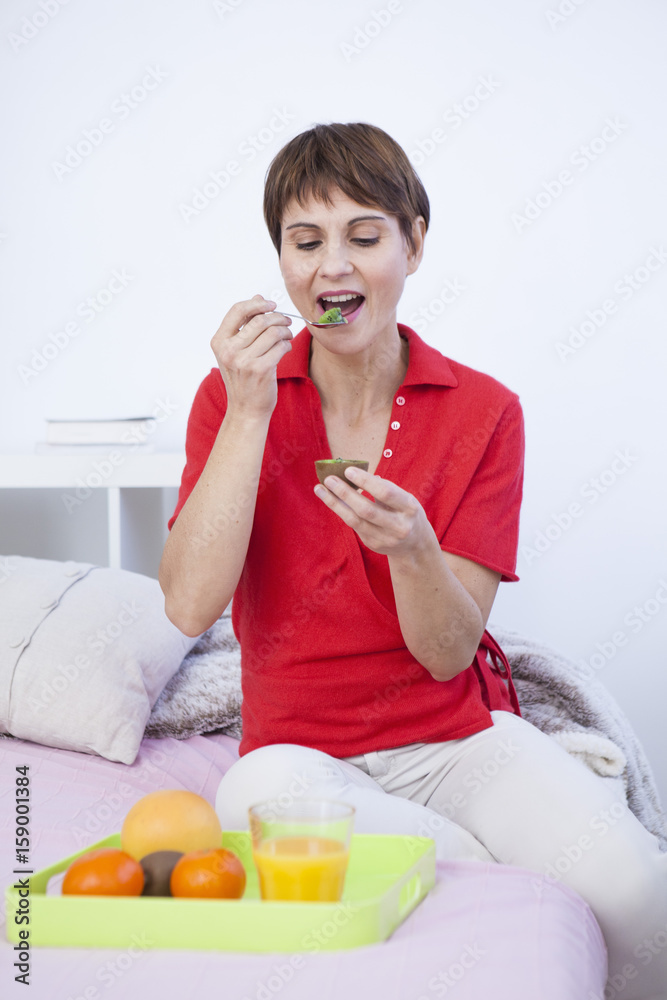 Woman eating a kiwi fruit