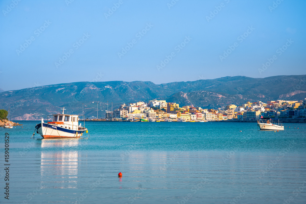 Small natural harbor with anchored fishing boats with the beautiful town of Agios Nikolaos at the background, Crete, Greece.