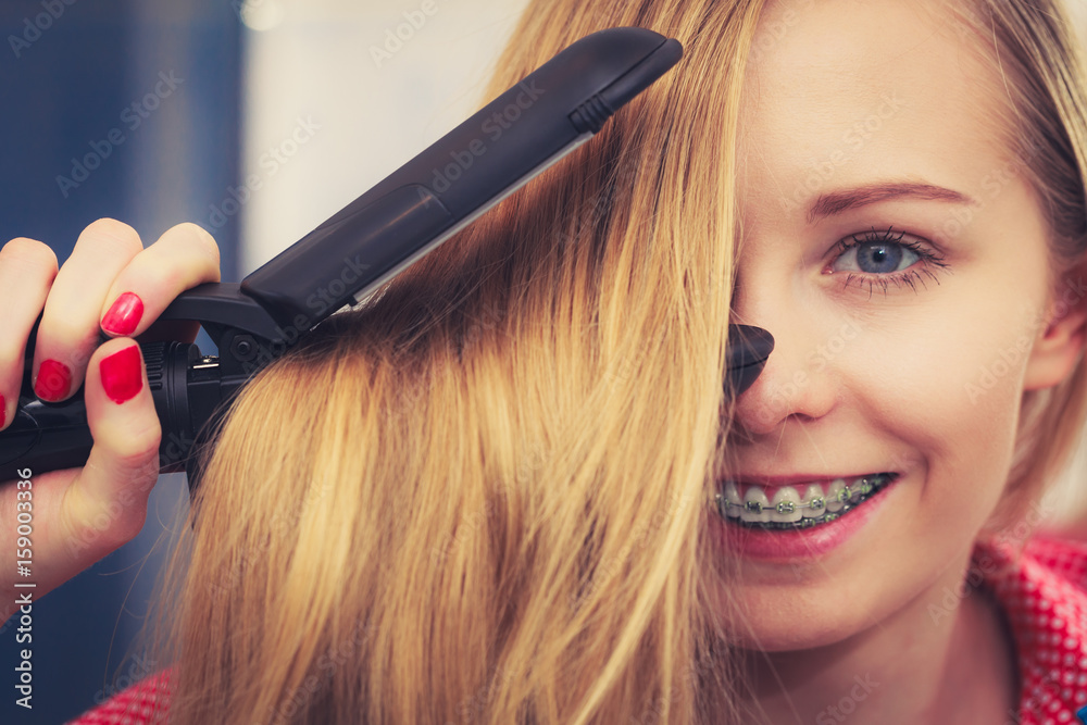Fototapeta premium Woman straightening her long blond hair