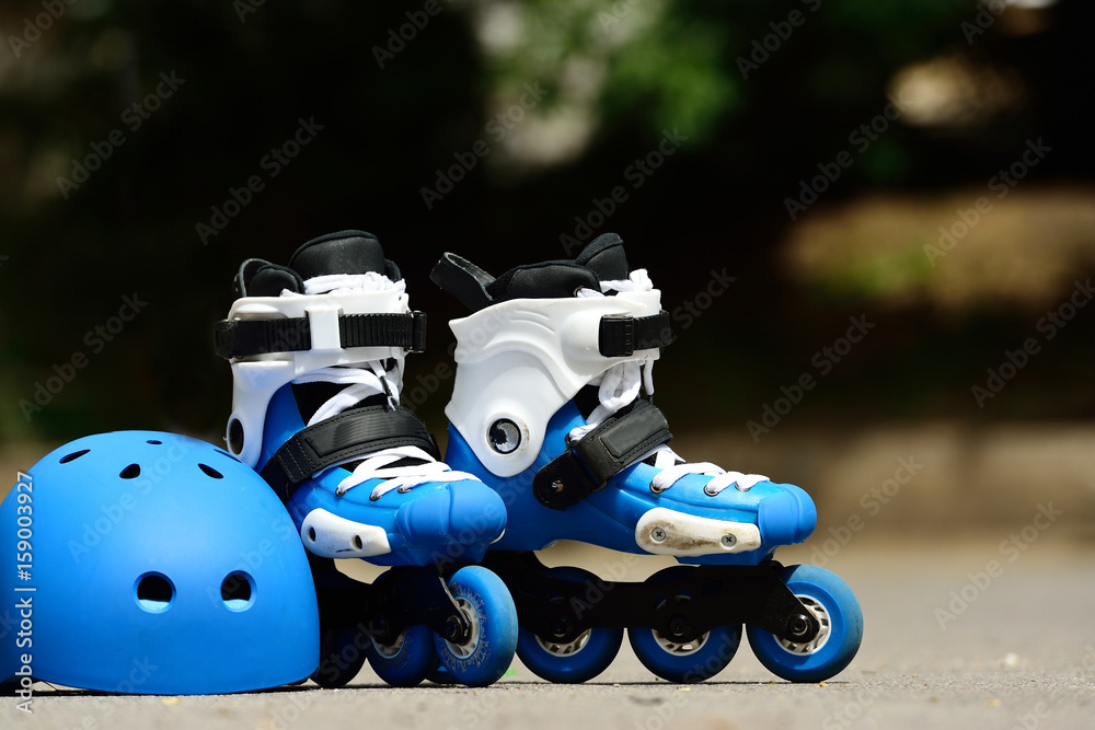 Roller inline skates with helmet in skate park on gray asphalt