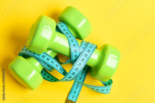 slim waist concept with dumbbells and measuring tape