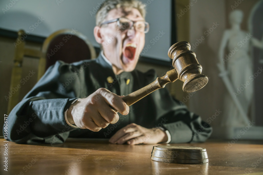 angry man a judge with a hammer in his hand in the court room Stock