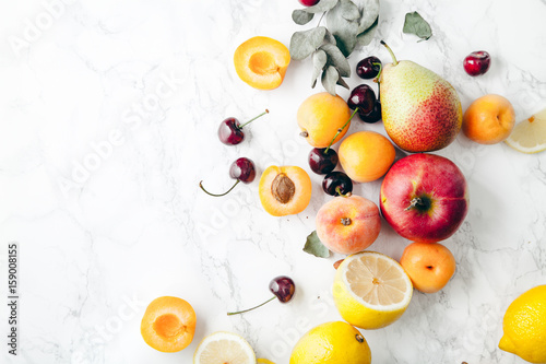Summer fruits assorted on white marble background. Fresh raw food concept. Copy space photo