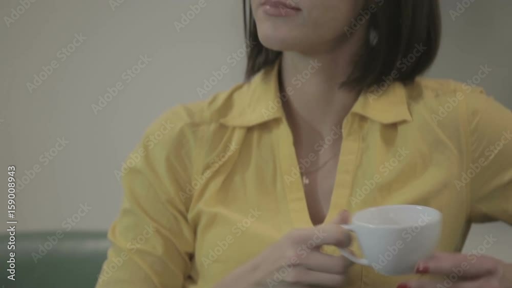 Beautiful brunette drinks a tea in the hotel on the green sofa Beautiful brunette drinks a tea in the hotel on the green sofa