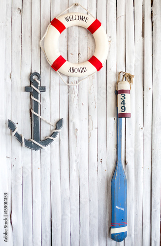 Life preserver, anchor and paddle on the white wall photo