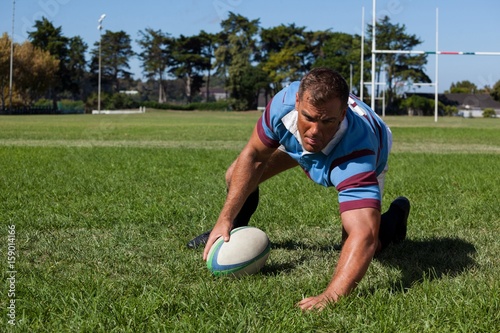 Player holding ball while playing rugby on field