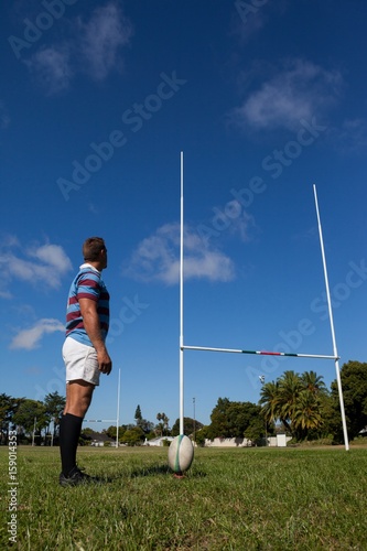 Side view of rugby player looking at goal post photo