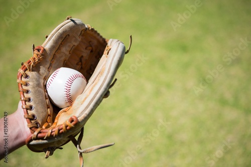 Cropped hand of baseball pitcher holding ball in glove