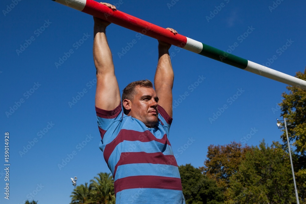 Low angle view of rugby player hanging on goal 