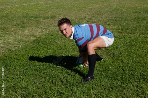 High angle view of rugby player crouching on field