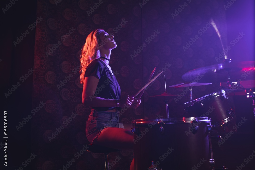 Ταπετσαρία Young female drummer performing in illuminated nightclub