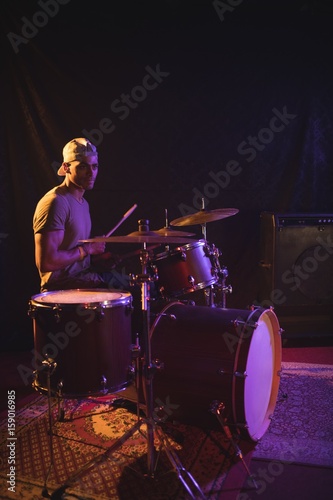 Confident male performing with drum kit in nightclub