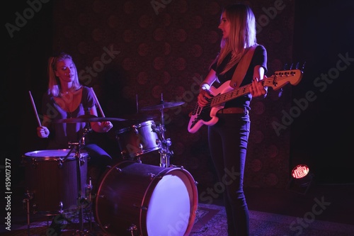 Confident female drummer and guitarist performing 