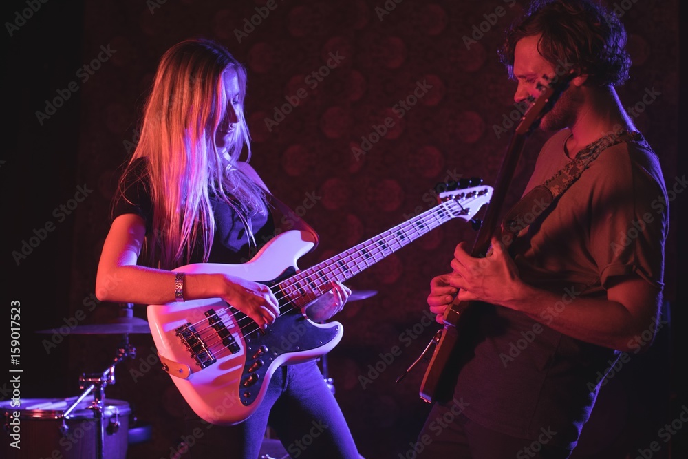 Fototapeta Male and female playing guitars in nightclub