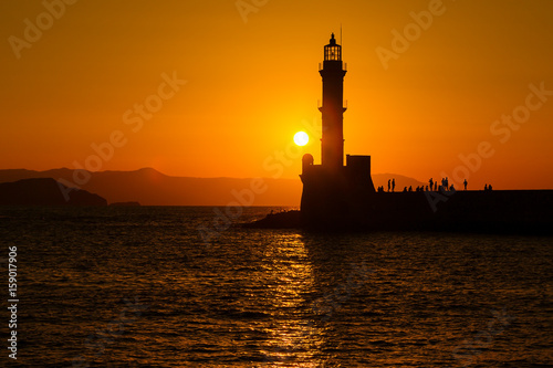 Silhouette of lighthouse in sea at sunset in the city of Chania, island of Crete, Greece. Beautiful seascape at sunset