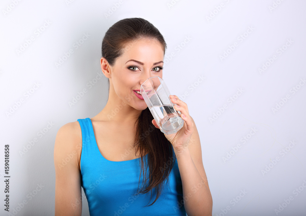 Young beautiful woman drinking fresh pure water from glass on blue background Young beautiful woman drinking fresh pure water from glass on blue background