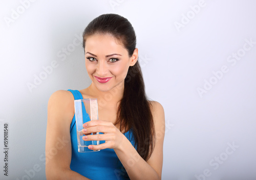 Cute beautiful woman holding the glass with pure water on blue background with happy smiling.