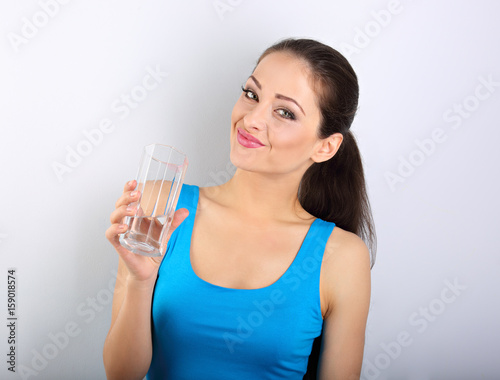 Young beautiful woman drinking fresh pure water from glass on blue backgound
