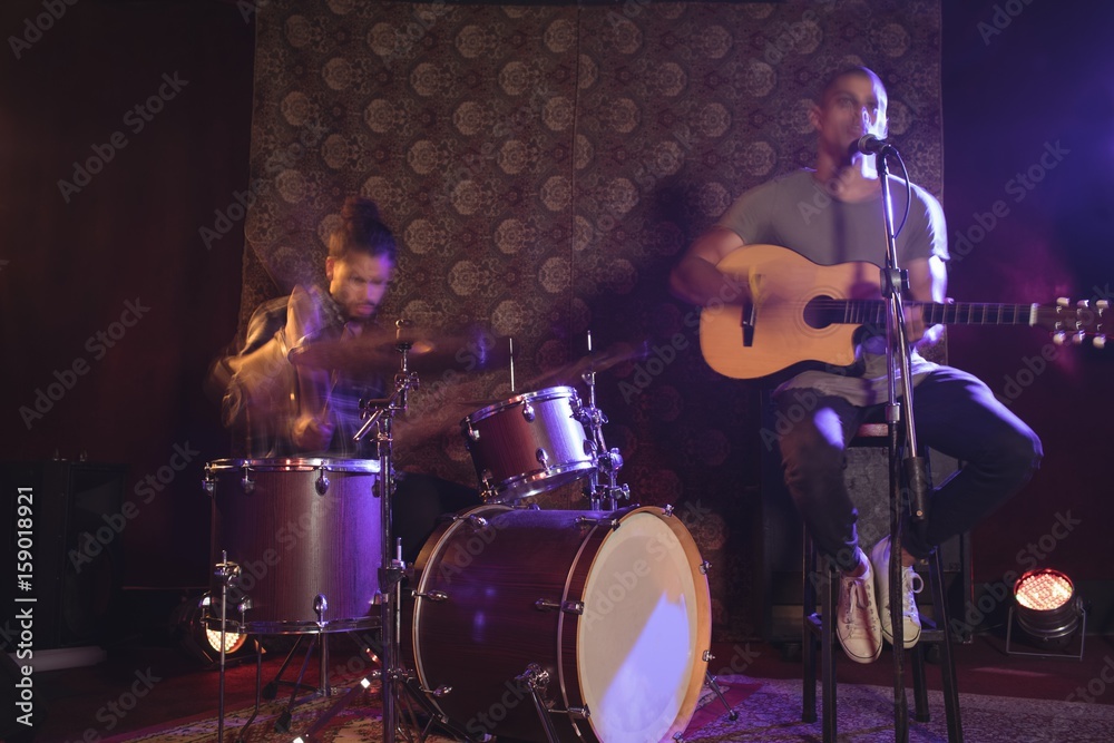 Fototapeta premium Male singer performing with drummer in nightclub