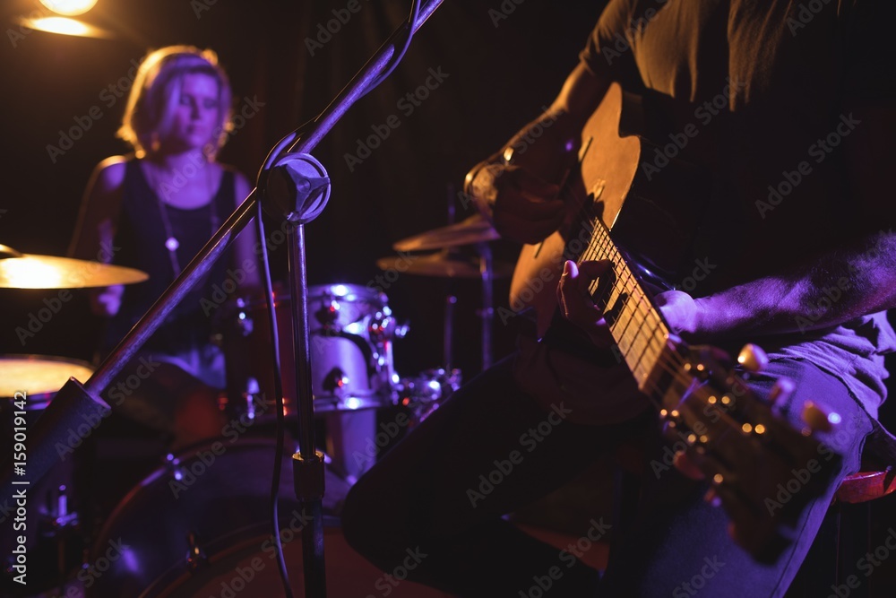 Fototapeta premium Mid section of male guitarist performing with female drummer