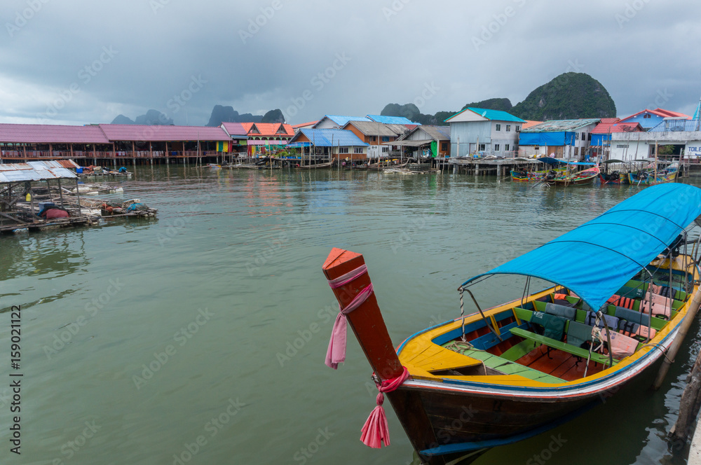 Longtail boat with houses and rainclouds in the background
