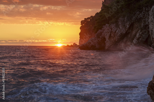 Sea landscape at sunset, with cliff and waves breaking on
