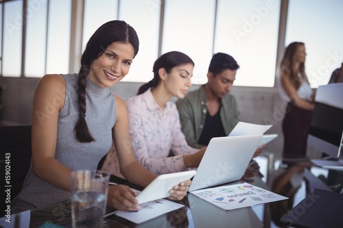 Portrait of young woman working with colleagues 