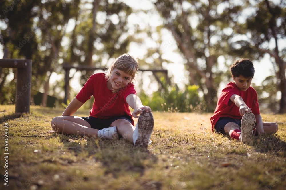 Fototapeta premium Happy kids performing stretching exercise during obstacle course