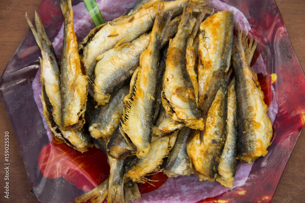 Fried baltic herring on a plate on wooden background Fried baltic herring on a plate on wooden background