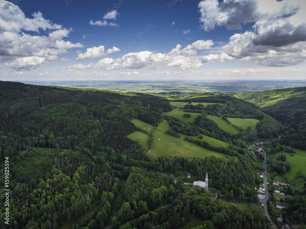 Aerial view of the summer time in mountains in border Poland and Czech Republic. Pine tree forest and clouds over blue sky. View from above.
